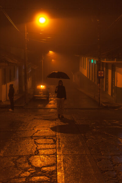 Frau steht nachts im Nebel auf einer Straße