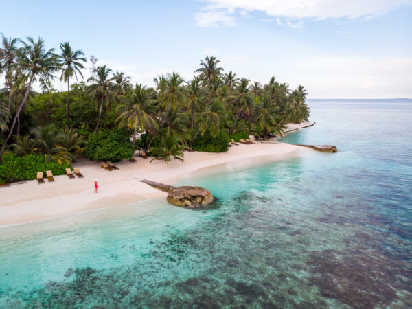 weißer Strand mit Palmen und vorgelagerten Korallenriffen