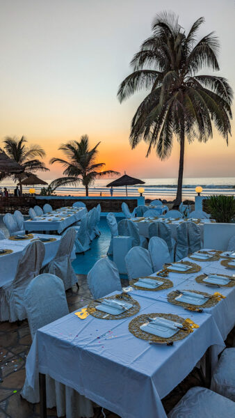 Festlich gedeckte Tische mit Palmen und Sonnenuntergang im Hintergrund