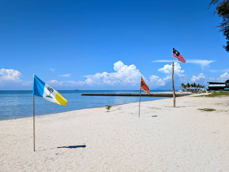 Verschiedene Flaggen im Sandstrand von Penang stecken