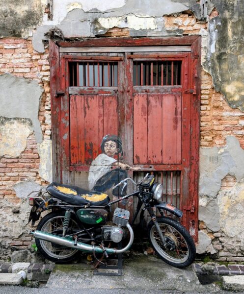 Eine Wandmalerei eines Jungen, der auf einem Motorrad sitzt, das an der Wand lehnt